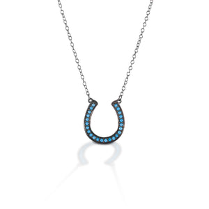 The Kelly Herd Turquoise Horseshoe Necklace stands out from the pack with its glowing turquoise colored stones against dark burnished sterling silver setting. Dare to be just a little different! Comes with a 16"-18" adjustable chain.  Features      Horseshoe pendant necklace     Dark burnished sterling silver     Blue stones     Adjustable 16-18" chain     11mm x 11mm